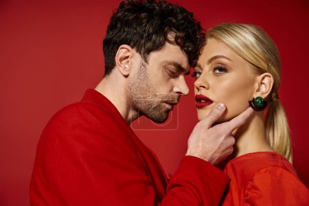 good looking man touching face of beautiful blonde woman with red lips on vibrant background