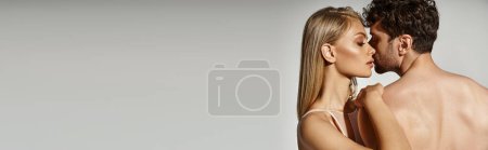 passionate and young woman with blonde hair seducing handsome man on grey backdrop, banner of couple Poster 689990124