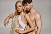 handsome man with muscular body putting hand on shoulder of blonde woman in bodysuit and blazer hoodie #689990556