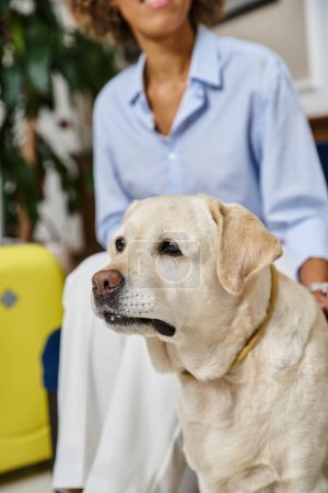 fröhliche Reisende, die auf den Check-in mit Labrador im haustierfreundlichen Hotel wartet, schwarze Frau mit Hund