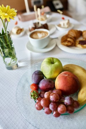 Hotel room service with fresh cappuccino and a variety of breakfast food, fresh flowers and fruits