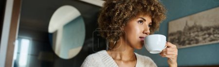 mujer afroamericana de pelo rizado bebiendo café mientras mira hacia otro lado en la habitación de hotel, banner de viaje