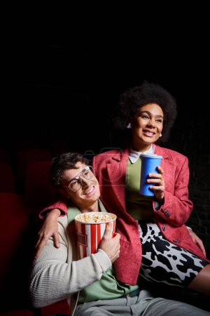 feliz pareja multiétnica en ropa retro tener gran tiempo en el cine en la fecha en el día de San Valentín