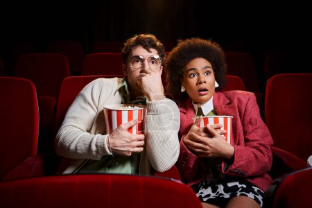 astonished shocked diverse couple in retro stylish attires watching movie at cinema, Valentines day
