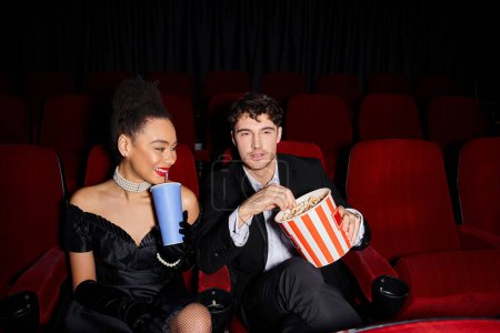 jeune couple attrayant et diversifié en tenue élégante profitant de leur date de la Saint Valentin au cinéma