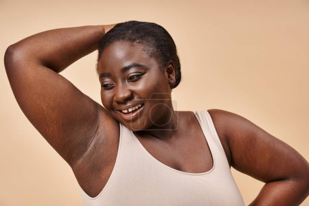 Photo for Confident plus size african american woman smiling with hand behind head on beige background - Royalty Free Image