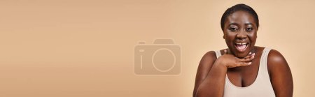 Photo for Excited plus size african american woman smiling with hand near her face on beige background, banner - Royalty Free Image