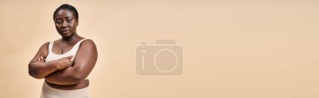 Téléchargez les photos : Femme confiante plus la taille en sous-vêtements beige posant avec les bras croisés, bannière positive du corps - en image libre de droit