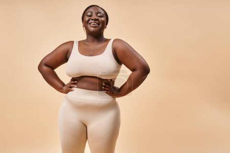 happy plus size woman in underwear posing with hands on hips, body positive and female empowerment