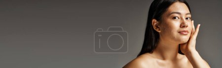 banner of young asian woman with skin issues and bare shoulders looking at camera on grey backdrop