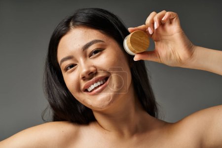 Téléchargez les photos : Jeune femme asiatique avec des cheveux bruns et l'acné peau sujette à regarder miroir dans la salle de bain, bannière - en image libre de droit