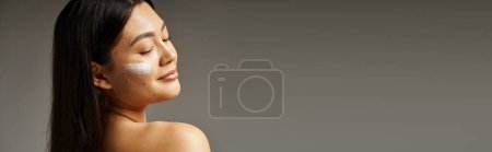 Téléchargez les photos : Jeune femme asiatique avec des cheveux bruns et l'acné peau sujette à regarder miroir dans la salle de bain, bannière - en image libre de droit