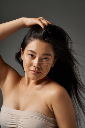junge asiatische Frau mit brünetten Haaren und zu Akne neigender Haut beim Anblick des Spiegels im Badezimmer, Banner