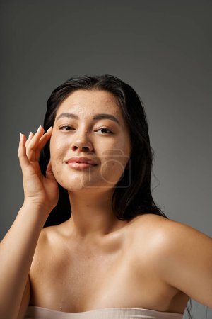 young asian woman with brunette hair and acne prone skin looking at mirror in bathroom, banner
