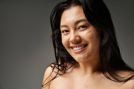 Foto de Mujer asiática joven con pelo morena y piel propensa al acné mirando el espejo en el baño, pancarta - Imagen libre de derechos