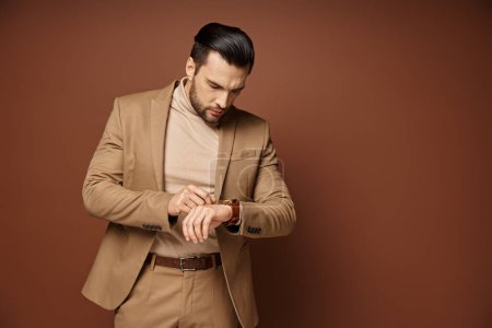 handsome man in elegant attire looking at his wristwatch on beige background, time management