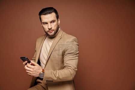 Foto de Hombre de negocios guapo en traje elegante comprobar teléfono inteligente sobre fondo beige, medios de comunicación social - Imagen libre de derechos
