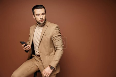 distracted businessman in elegant attire holding his smartphone on beige background, social media
