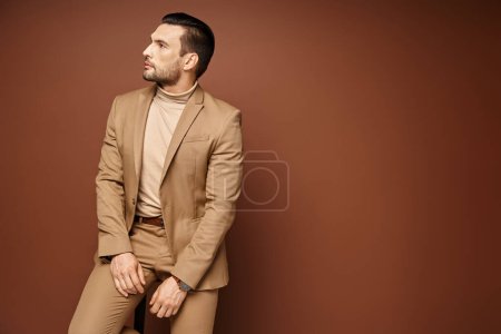 handsome man in elegant attire looking away while sitting on chair on beige background, think puzzle 692773914