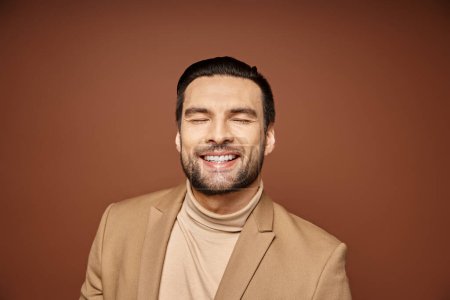 Porträt eines attraktiven Mannes in eleganter Kleidung, der mit geschlossenen Augen auf beigem Hintergrund lächelt