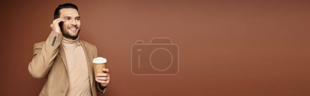 Téléchargez les photos : Homme heureux en tenue élégante tenant café et ayant appel sur smartphone sur fond beige, bannière - en image libre de droit