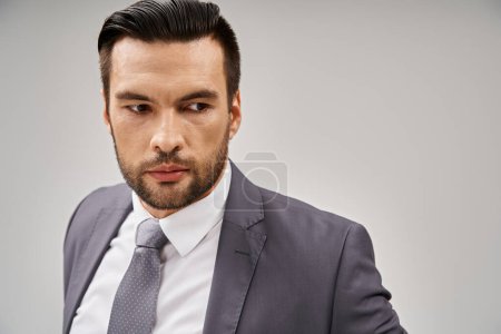 portrait of handsome businessman in stylish attire posing on grey background, tailored suit