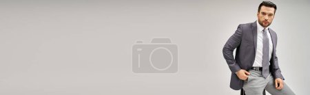 Téléchargez les photos : Homme d'affaires beau et confiant en tenue formelle appuyé sur un tabouret haut sur fond gris, bannière - en image libre de droit