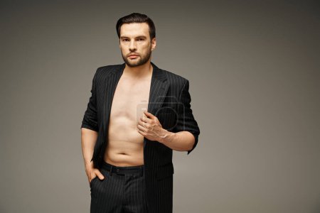 Mode-Statement-Konzept, gutaussehender und hemdsloser Mann im Nadelstreifenanzug posiert auf grauem Hintergrund