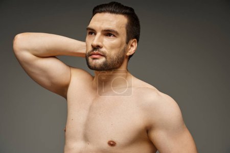 Porträt eines muskulösen und hemdlosen Mannes mit nackter Brust und Borsten, der auf grauem Hintergrund posiert