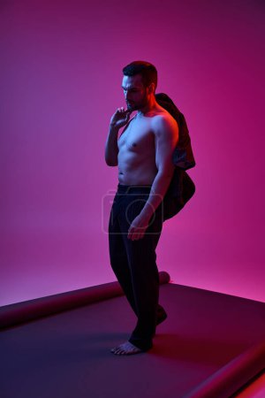 Hemdloser Mann um die 30 posiert mit nackter Brust in Hose und Blazer auf lila Hintergrund