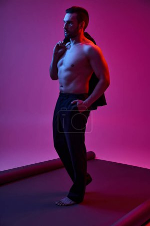 homme torse nu et poil tenant veste tout en posant avec la main dans la poche sur violet