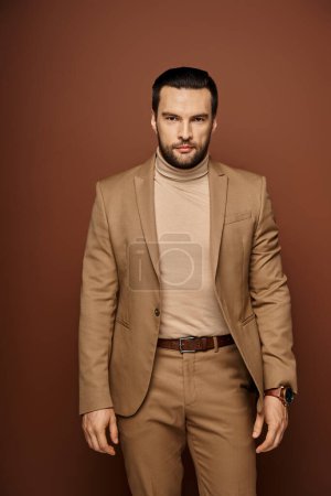 portrait d'homme confiant et beau avec soies en costume élégant posant sur fond beige