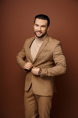 Porträt eines selbstbewussten und gut aussehenden Mannes mit Borsten im stylischen Anzug, der auf beigem Hintergrund posiert