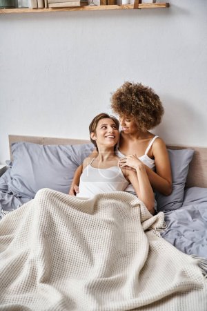 multicultural lesbian young couple enjoying morning time together in bedroom, cheerful moments