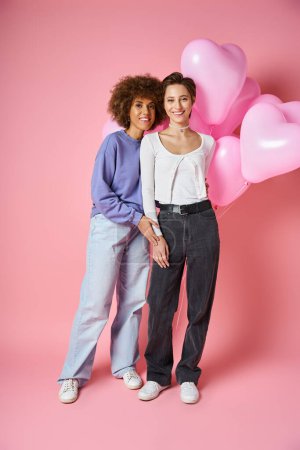 Concept de Saint-Valentin, couple lesbien multiculturel joyeux souriant près de ballons en forme de coeur