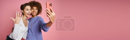 happy lesbian woman showing engagement ring on her finger while taking selfie with fiancee, banner