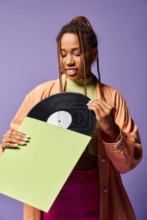 joven afroamericana de unos 20 años con rastas admirando el disco de vinilo con una expresión alegre