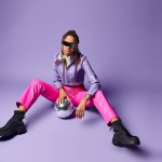 stylish african american girl in trendy sunglasses and headphones sitting near disco ball on purple