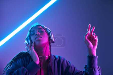 ekstatische Afroamerikanerin mit Kopfhörern genießt Musik im Studio mit Leuchtstoffröhren