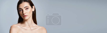 A young caucasian woman with long, brunette hair gracefully posing for a portrait in a studio setting, banner