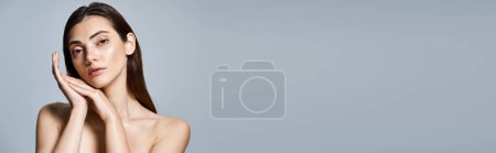A young Caucasian woman with brunette hair captivatingly poses with hands on her face in a studio setting, banner