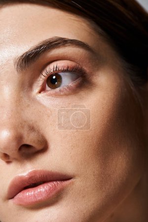Eine junge kaukasische Frau mit sauberer Haut ist in einer Nahaufnahme zu sehen, die ihre bezaubernden braunen Augen hervorhebt.