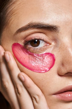 close up view of a young Caucasian woman with pink eye patch in a studio setting.