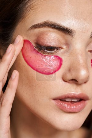 Foto de Una joven mujer caucásica con piel limpia y parche rosa en la cara en un entorno de estudio. - Imagen libre de derechos