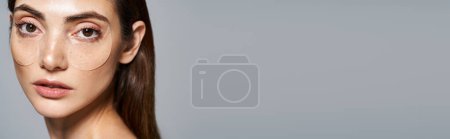 Téléchargez les photos : Une jeune femme caucasienne aux cheveux bruns dans un décor studio, avec des patchs sous les yeux, bannière - en image libre de droit