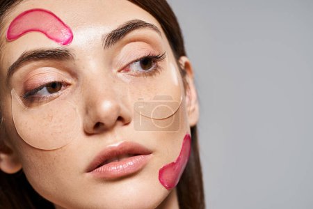 Téléchargez les photos : Une jeune femme caucasienne aux cheveux bruns et à la peau propre portant des taches hydratantes roses sur le visage - en image libre de droit
