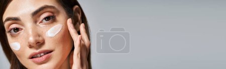 Téléchargez les photos : Une jeune femme caucasienne aux cheveux bruns sourit avec une crème sur le visage, bannière - en image libre de droit