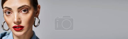 Téléchargez les photos : Une jeune femme caucasienne aux cheveux bruns portant une chemise bleue et de grandes boucles d'oreilles cerceau, exsudant élégance et style, bannière - en image libre de droit