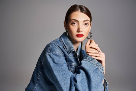 Photo for A young Caucasian woman with brunette hair in a stylish jean jacket and bold red lipstick. - Royalty Free Image