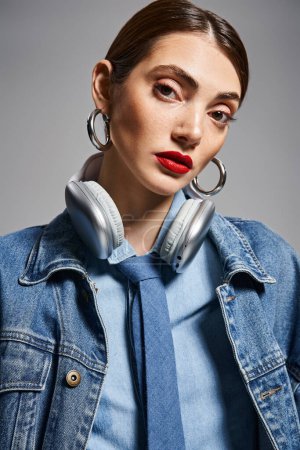 A young Caucasian woman with brunette hair in headphones and a denim jacket.